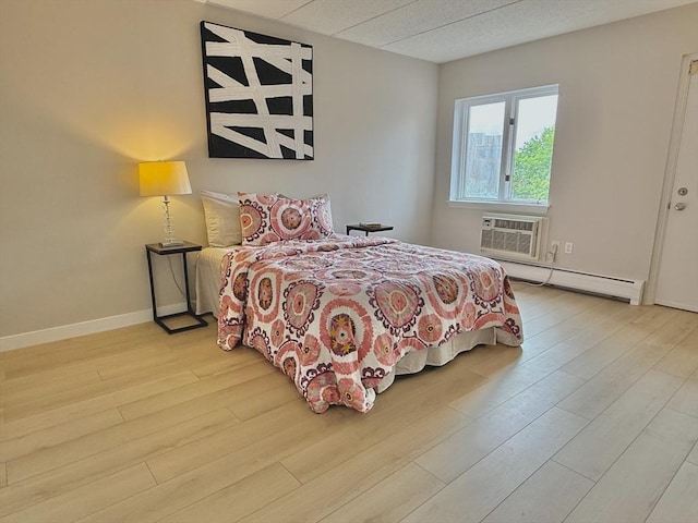 180 Green St Unit 415, Melrose, MA 02176 - bedroom featuring a baseboard radiator, wood finished floors, and a wall mounted air conditioner