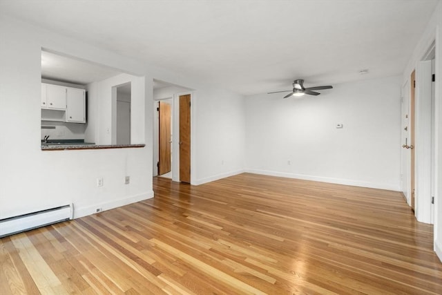 150 Main St Unit 12, Stoneham, MA 02180 - unfurnished living room with a ceiling fan, light wood-style floors, baseboards, and a baseboard heating unit