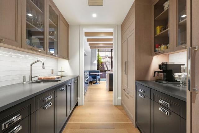 kitchen featuring tasteful backsplash, stainless steel range oven, dark brown cabinets, light hardwood / wood-style flooring, and sink