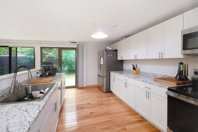 238 Brown Bear Xing Unit 238, Acton, MA 01720 - kitchen featuring stainless steel appliances, a sink, light wood-style floors, white cabinets, and light stone countertops