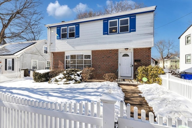 traditional home featuring a fenced front yard and brick siding