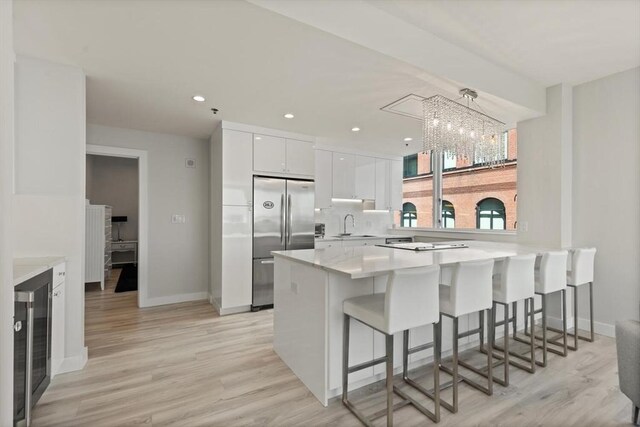 234 Causeway St Apt 709, Boston, MA 02114 - kitchen featuring a kitchen breakfast bar, white cabinets, a peninsula, a notable chandelier, and stainless steel fridge