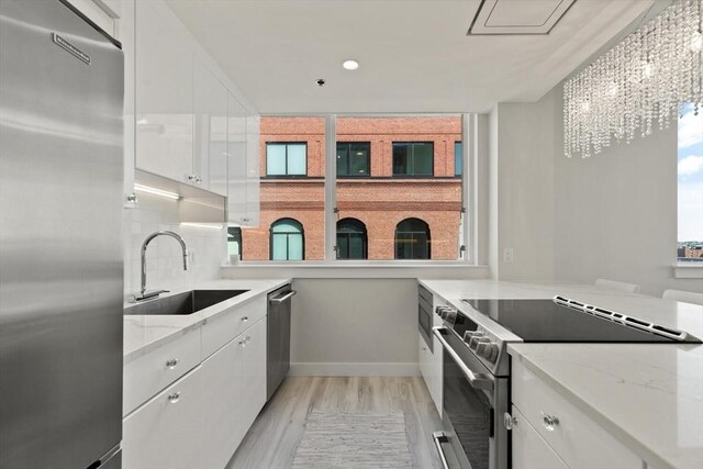 234 Causeway St Apt 709, Boston, MA 02114 - kitchen featuring light wood-type flooring, a sink, white cabinets, an inviting chandelier, and stainless steel appliances