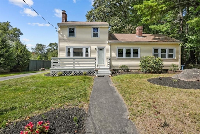 view of front of home featuring a wooden deck, a front lawn, a chimney, and fence