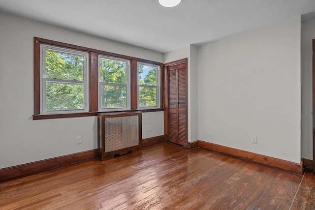 unfurnished room featuring hardwood / wood-style flooring, radiator heating unit, and baseboards