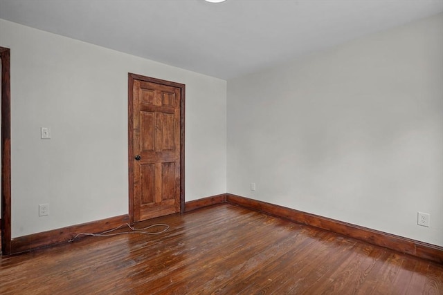 unfurnished room with baseboards and wood-type flooring