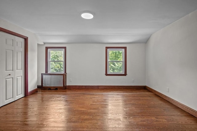 unfurnished room with wood finished floors, baseboards, and a healthy amount of sunlight