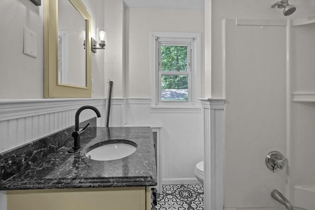 full bathroom with vanity, tub / shower combination, tile patterned flooring, wainscoting, and toilet