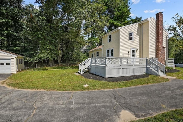 view of property exterior with a wooden deck, a lawn, and a chimney