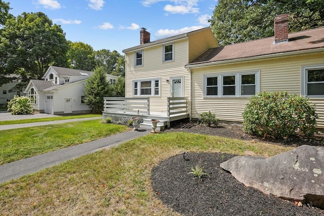 view of front of house with a deck, a front yard, and a chimney