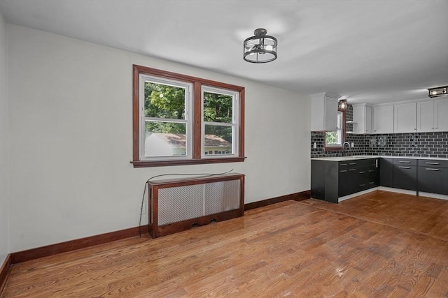 kitchen with decorative backsplash, radiator, light countertops, and wood finished floors