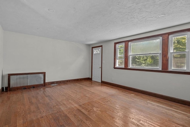 empty room featuring wood finished floors, baseboards, and a textured ceiling