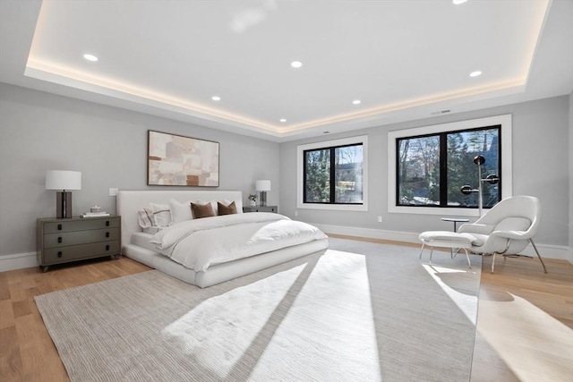 bedroom featuring light wood-type flooring and a raised ceiling