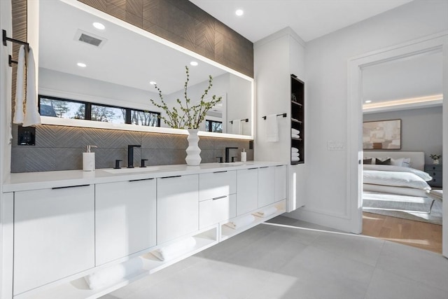 interior space with backsplash, white cabinetry, sink, and tile patterned floors