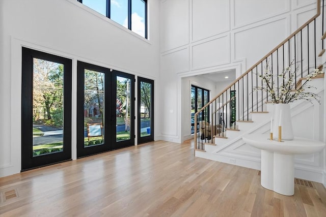 entryway featuring french doors, light hardwood / wood-style flooring, and a high ceiling