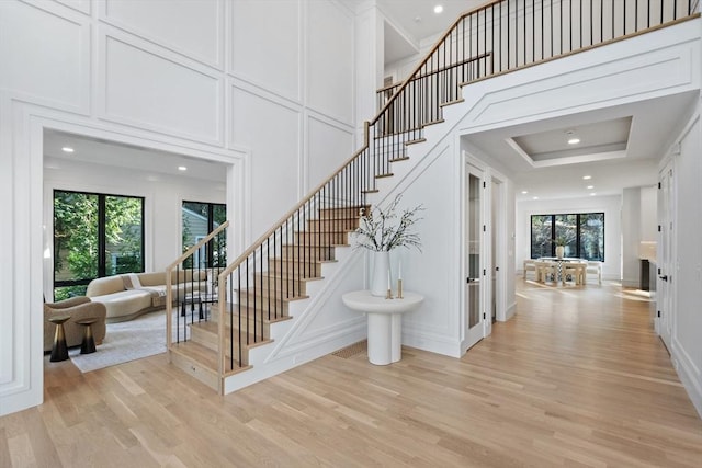 staircase with hardwood / wood-style floors and a towering ceiling