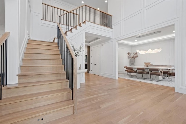 staircase with wood-type flooring and a high ceiling