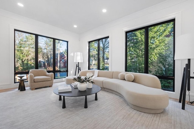 living room with light hardwood / wood-style floors, crown molding, and a healthy amount of sunlight