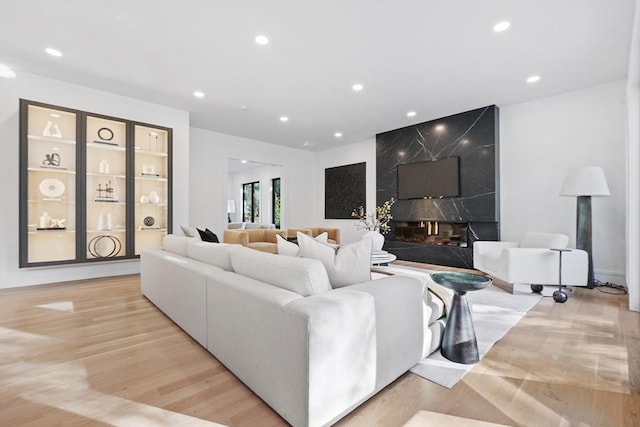 living room with a high end fireplace and light hardwood / wood-style flooring