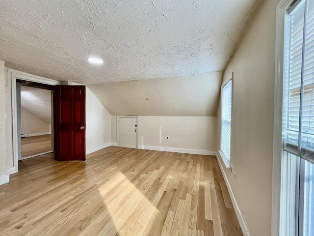 bonus room featuring light wood-type flooring, a textured ceiling, and vaulted ceiling