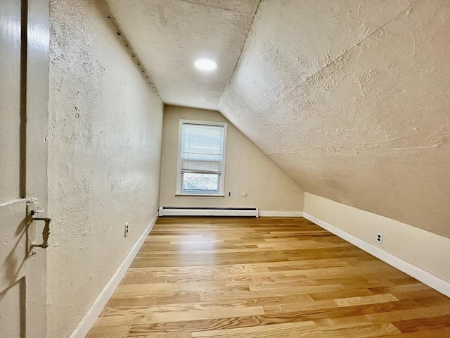 bonus room featuring hardwood / wood-style flooring, vaulted ceiling, and a baseboard heating unit