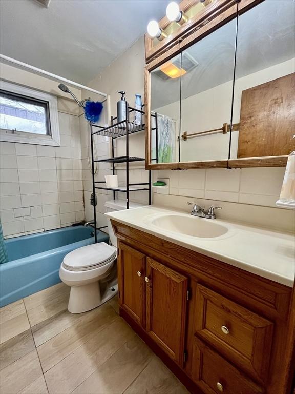 full bathroom featuring vanity, backsplash, tile patterned floors, shower / bath combination with curtain, and toilet