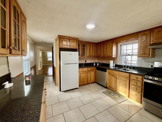 kitchen featuring a textured ceiling, range hood, sink, and appliances with stainless steel finishes