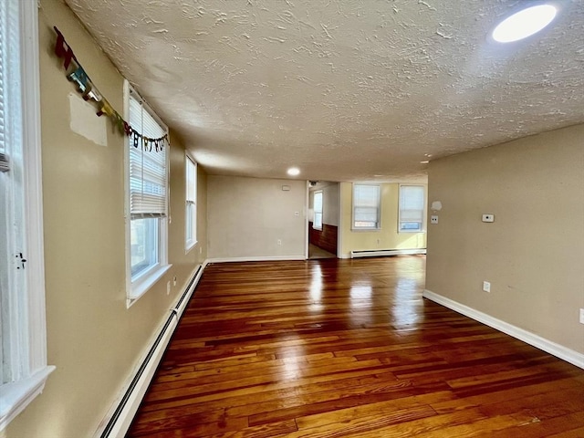 spare room featuring a textured ceiling, a baseboard radiator, and dark hardwood / wood-style floors