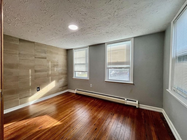 unfurnished room with baseboard heating, a textured ceiling, and hardwood / wood-style flooring