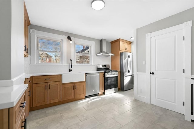 kitchen with stainless steel appliances, sink, and wall chimney exhaust hood