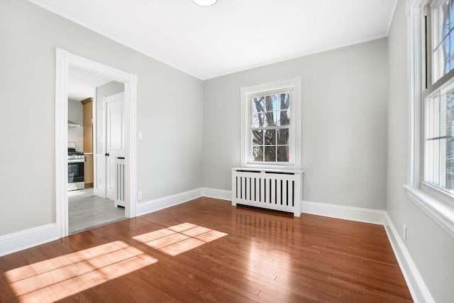 unfurnished room featuring hardwood / wood-style floors and radiator heating unit