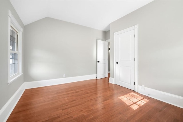 spare room featuring vaulted ceiling and hardwood / wood-style floors