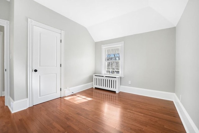 interior space featuring lofted ceiling, radiator, and hardwood / wood-style floors