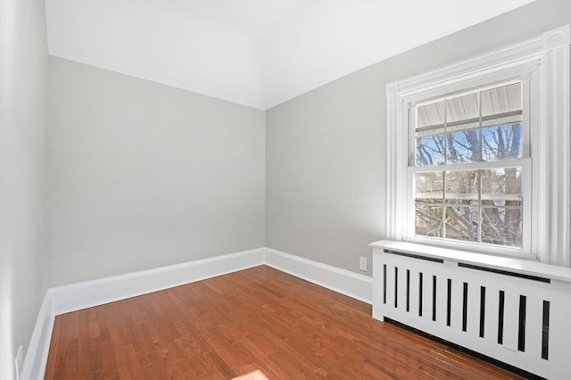 empty room with hardwood / wood-style flooring and radiator