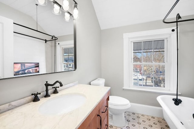 bathroom featuring vaulted ceiling, a washtub, vanity, and toilet