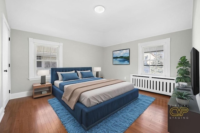 bedroom with radiator heating unit and dark hardwood / wood-style floors