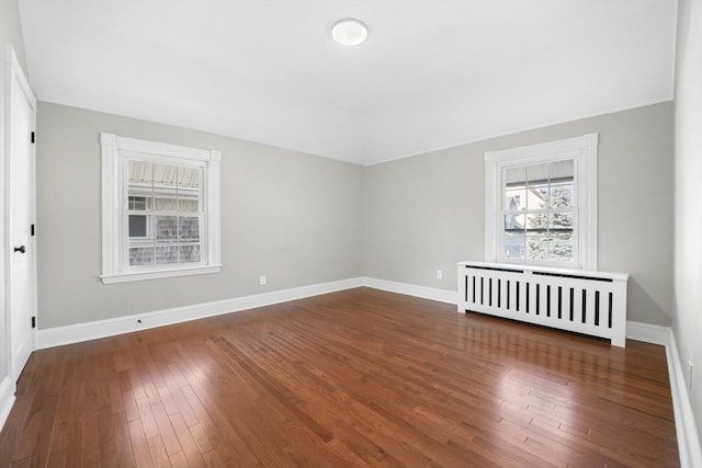 empty room featuring radiator and dark hardwood / wood-style flooring