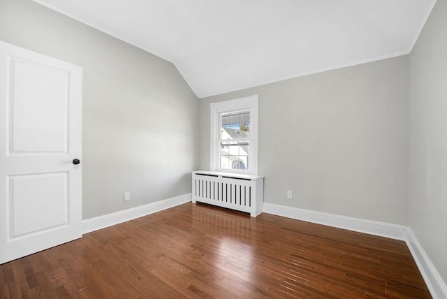 spare room featuring vaulted ceiling, wood-type flooring, and radiator heating unit