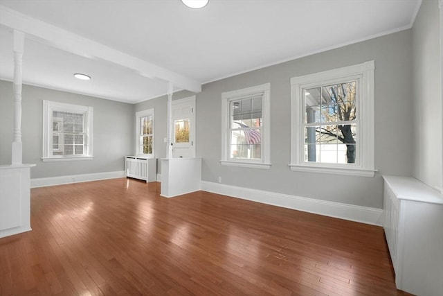 unfurnished living room featuring hardwood / wood-style flooring, ornamental molding, and radiator