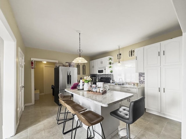 16 Willoughby St, Lawrence, MA 01841 - kitchen featuring white microwave, freestanding refrigerator, a sink, a kitchen bar, and white cabinetry