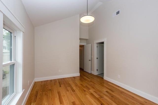 empty room featuring high vaulted ceiling and light wood-type flooring