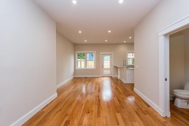 unfurnished living room with sink and light hardwood / wood-style floors