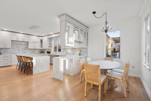 dining area with a chandelier, light hardwood / wood-style flooring, and crown molding