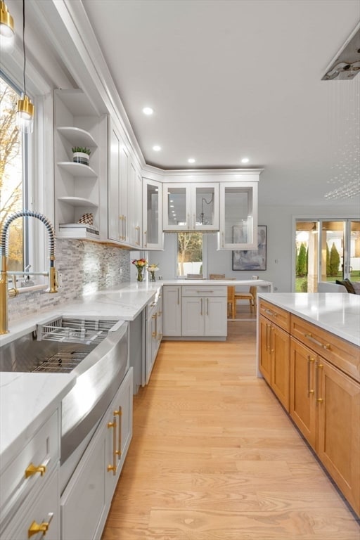 kitchen featuring white cabinetry, plenty of natural light, light hardwood / wood-style floors, and light stone countertops