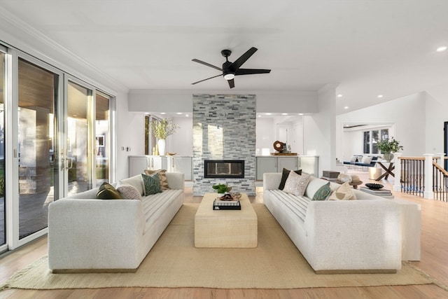 living room with ornamental molding, light wood-type flooring, ceiling fan, and a fireplace