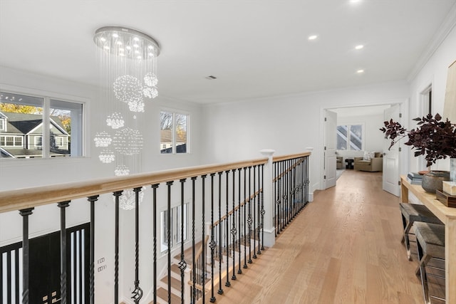 corridor featuring ornamental molding, light hardwood / wood-style flooring, and a notable chandelier