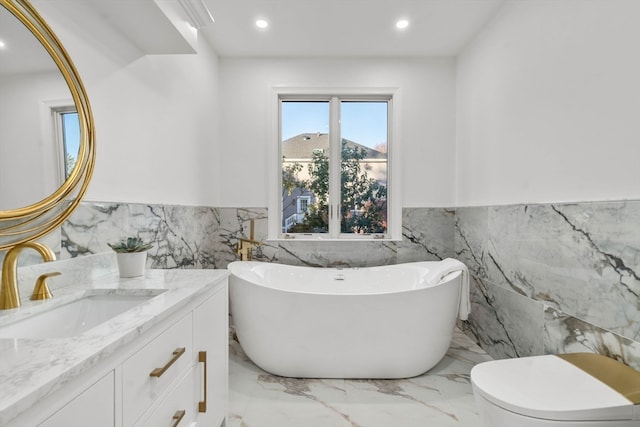 bathroom with a bathtub, vanity, tile walls, and toilet