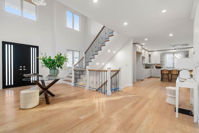 entrance foyer featuring a towering ceiling and light wood-type flooring