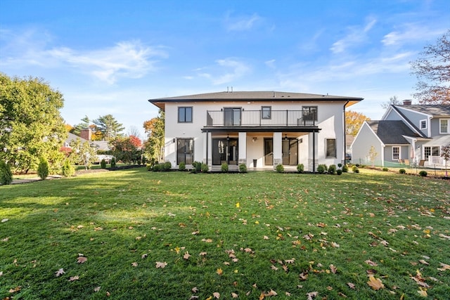 rear view of property with a balcony and a yard