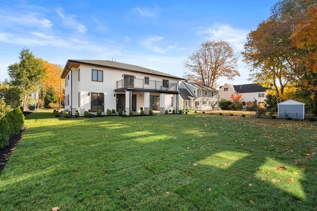 rear view of property featuring a balcony and a lawn